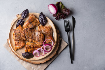 Catfish kebab. Shashlik with roasted fish on on a round plate with red onion and basil.
