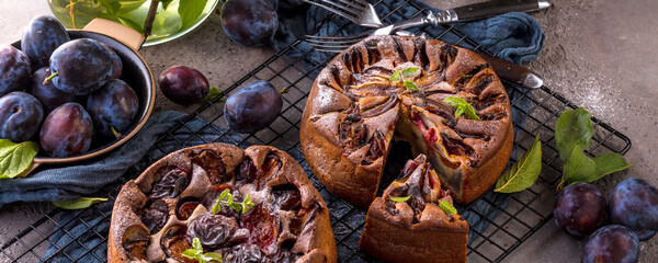 rustic plum cake on dark background , top view