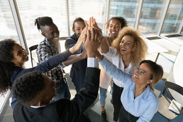 Above top view happy friendly young african american diverse colleagues joining hands in air,...