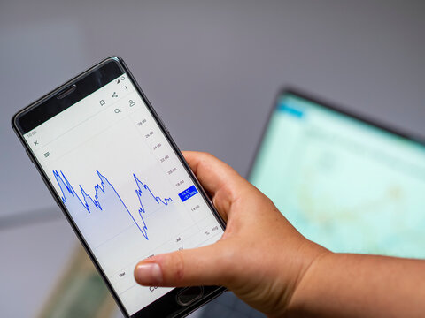 Businessperson checking a stock market graph on a cellphone. Finance and economy going bad, losing money. stock statistics seen on a mobile phone screen for analysis. Project financial stats sales