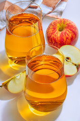 Glass of apple juice and fresh apple on white background.