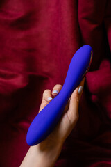 Woman in bedroom holding vibrator in hand.