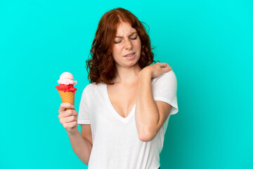 Teenager reddish woman with a cornet ice cream isolated on blue background suffering from pain in shoulder for having made an effort