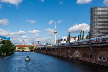Fototapeta premium cityscape image of berlin with a view of the television tower, the spree river and a train on a railway bridge