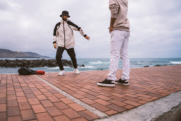 Two Caucasian guys, dressed in casual outfits, dance shuffle in the middle of the street
