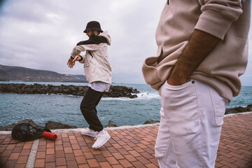 Fototapeta premium Two Caucasian guys, dressed in casual outfits, dance shuffle in the middle of the street