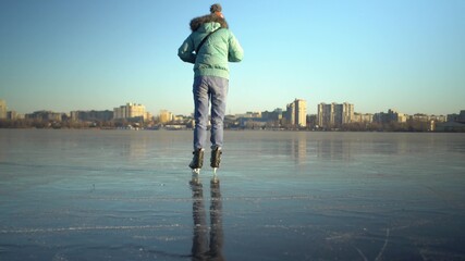Adult caucasian woman in blue jacket and light jeans skates on ice