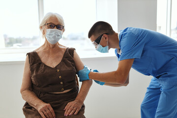 Fototapeta premium male doctor injects an elderly woman with a vaccine covid-19 hospital