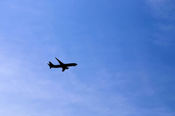 Airplane Silhouette against a blue sky. Bottom View of a commercial Airplane flying in the Sky..No logo or brand is visible. Copy space available.