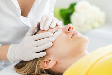 Woman receiving eyelash extension in beauty salon