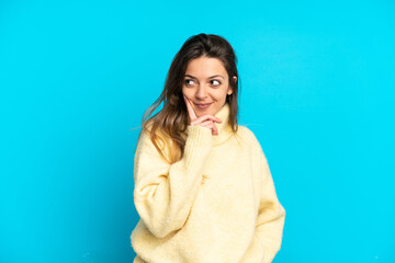 Young caucasian woman isolated on blue background thinking an idea while looking up