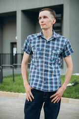 A young man at a photo shoot c in a checkered shirt with short sleeves.
