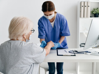 Fototapeta premium an elderly woman at the doctor's appointment gives an injection of covid passport coronavirus