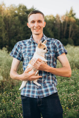 Naklejka na ściany i meble A young man poses with a Chihuahua dog at a photo shoot. 