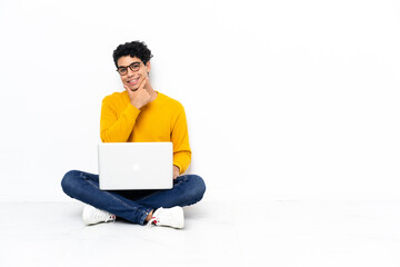 Venezuelan man sitting on the floor with laptop happy and smiling