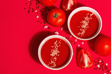 Tomato soup with sesame seeds in bowls on a red background