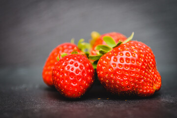 Group of red strawberries on a grey background.
