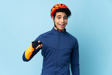 Venezuelan cyclist man isolated on blue background surprised and pointing front - obrazy, fototapety, plakaty