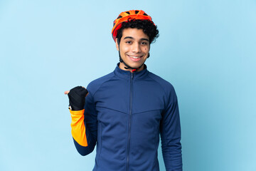 Venezuelan cyclist man isolated on blue background pointing to the side to present a product