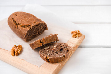 Sliced homemade walnut bread on white wooden table