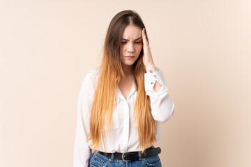 Young caucasian woman isolated on beige background with headache