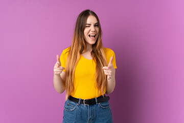 Young caucasian woman isolated on purple background pointing to the front and smiling