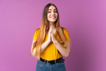 Young caucasian woman isolated on purple background keeps palm together. Person asks for something