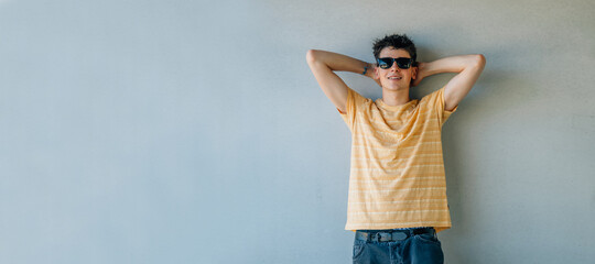 relaxed teen boy in sunglasses leaning on the wall