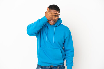 Young latin man isolated on white background covering eyes by hands and smiling
