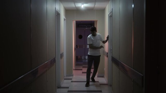 A man with a lack of coordination of movement slowly walks along the corridors of the hospital