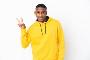 Young latin man isolated on white background smiling and showing victory sign