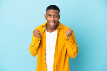 Young latin man isolated on blue background celebrating a victory in winner position