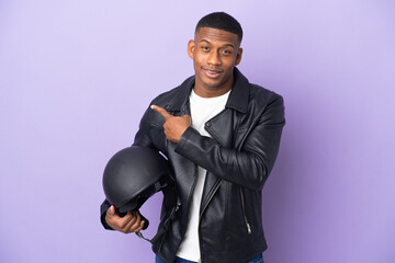 Latin man with a motorcycle helmet isolated on purple background pointing to the side to present a product