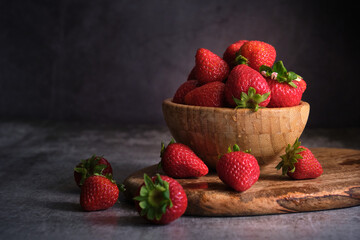 strawberries in a wooden bowl on a gray background