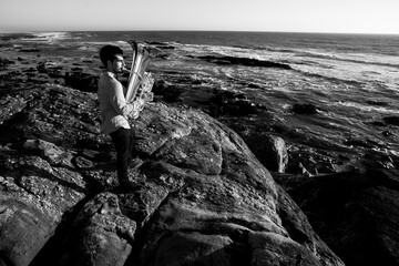 A musician play jazz a tuba on the seashore. Black and white photo.