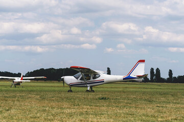 Planes on the airfield waiting to go into the air. Conventionally laid out single-engine, high-wing light aircraft with seating for two passengers towing planes