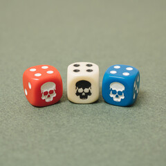 Arranged dice red, blue and white with skull one next to another on green background. Minimal design.