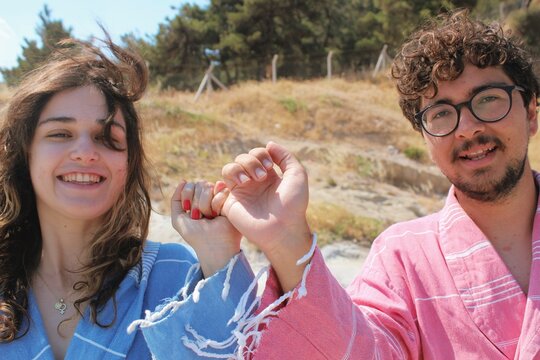 Portrait of young friends wearing colors of gender identity pink & blue robes together , holding pinkie fingers halay dance *2