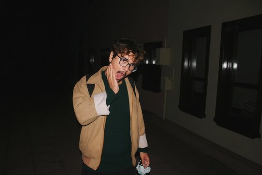 Portrait of young man funny surprised face expression flash at night