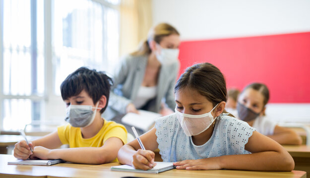 Diligent Tween Girl In Protective Mask Studying In School With Classmates. New Life Reality In Coronavirus Pandemic..