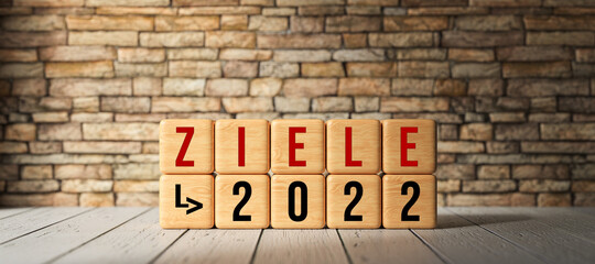 Fototapeta na wymiar cubes with German message for GOALS 2022 on wooden base and brick wall background