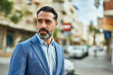 Naklejka premium Middle age businessman with relaxed expression standing at the city.