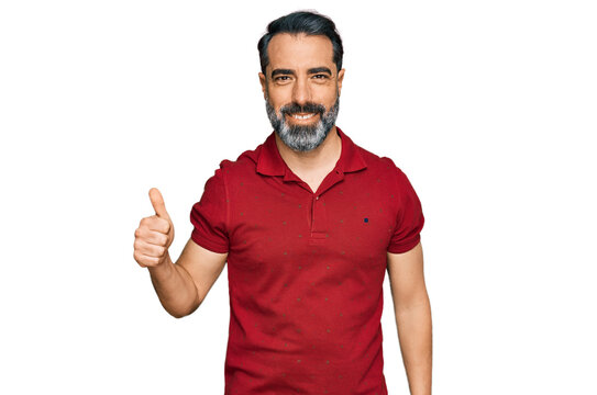 Middle aged man with beard wearing casual red t shirt smiling happy and positive, thumb up doing excellent and approval sign