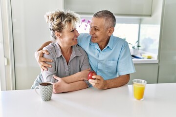Senior caucasian couple smiling happy having breakfast at the kitchen.