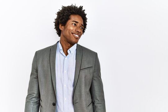 Young African American Man Wearing Business Jacket Over Isolated White Background Looking Away To Side With Smile On Face, Natural Expression. Laughing Confident.