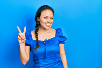 Young hispanic girl wearing casual clothes showing and pointing up with fingers number two while smiling confident and happy.