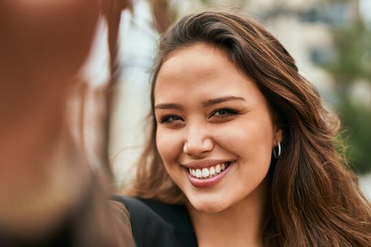 Young hispanic woman smiling happy making selfie by the camera at the city.