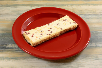 Greek Strawberry and peanut nougat snack bar on red plate on table