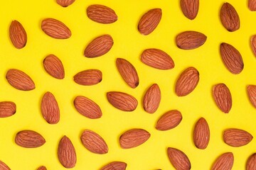 Top view of unshelled almond nuts kernels. Flat lay with food composition on yellow background.