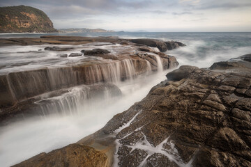 cascades of water falling down the rocks at the coast